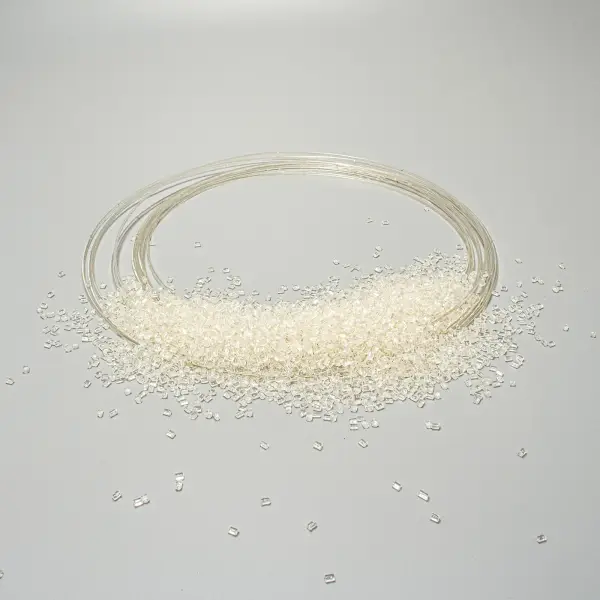Transparent plastic beads scattered on a grey surface next to a coiled transparent filament.