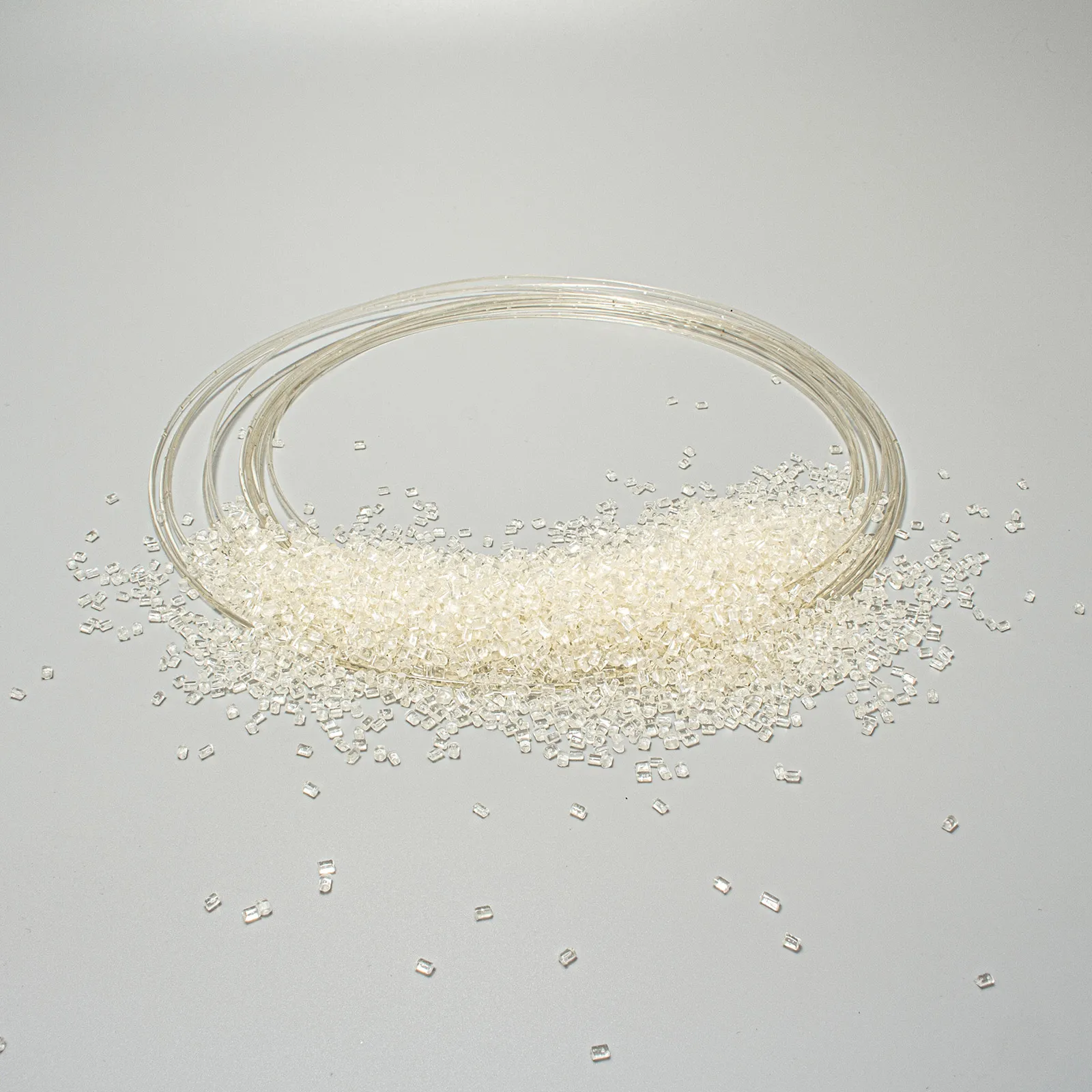 Transparent plastic beads scattered on a grey surface next to a coiled transparent filament.