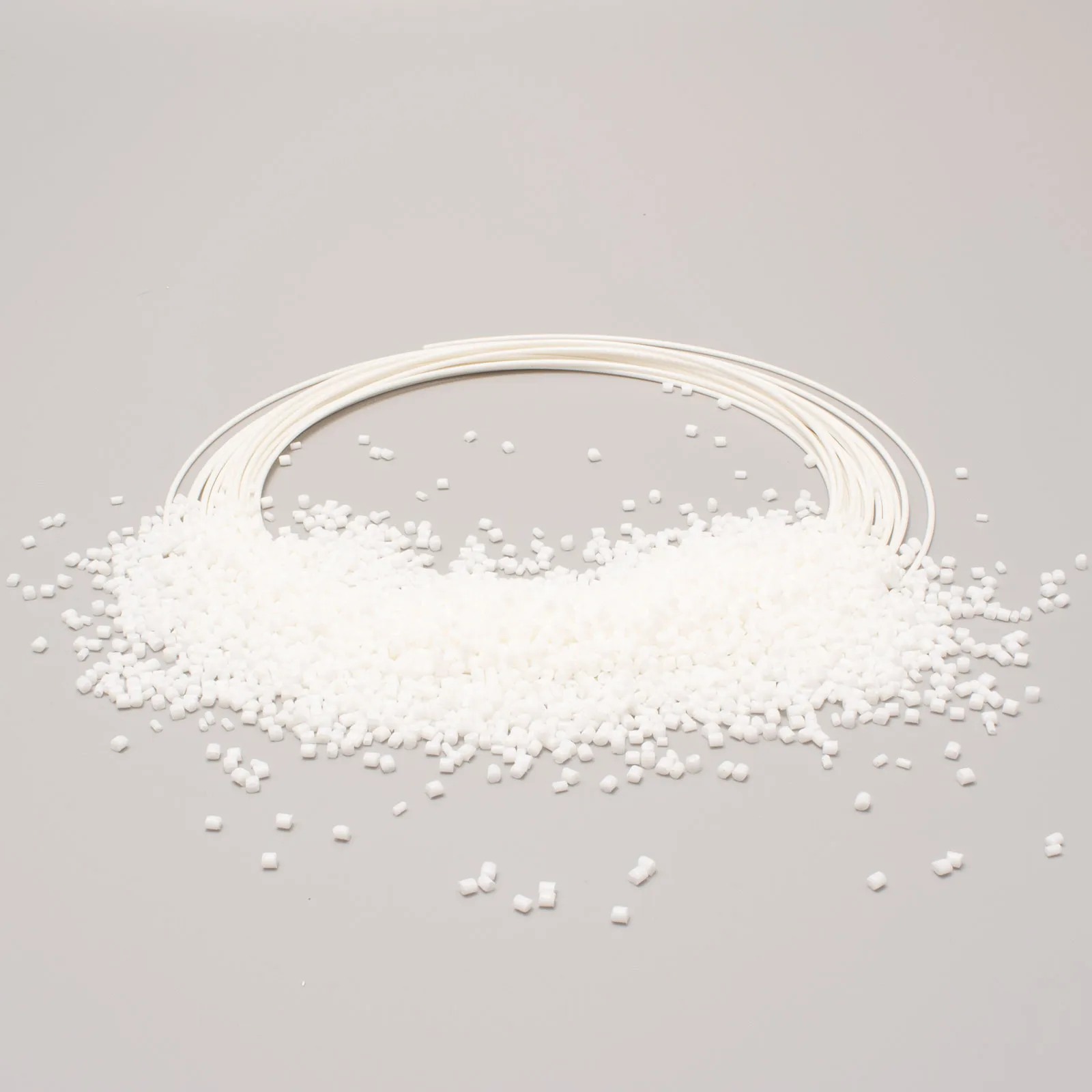 White plastic granules scattered next to small tubes on a light grey background.          Chiedi a ChatGPT