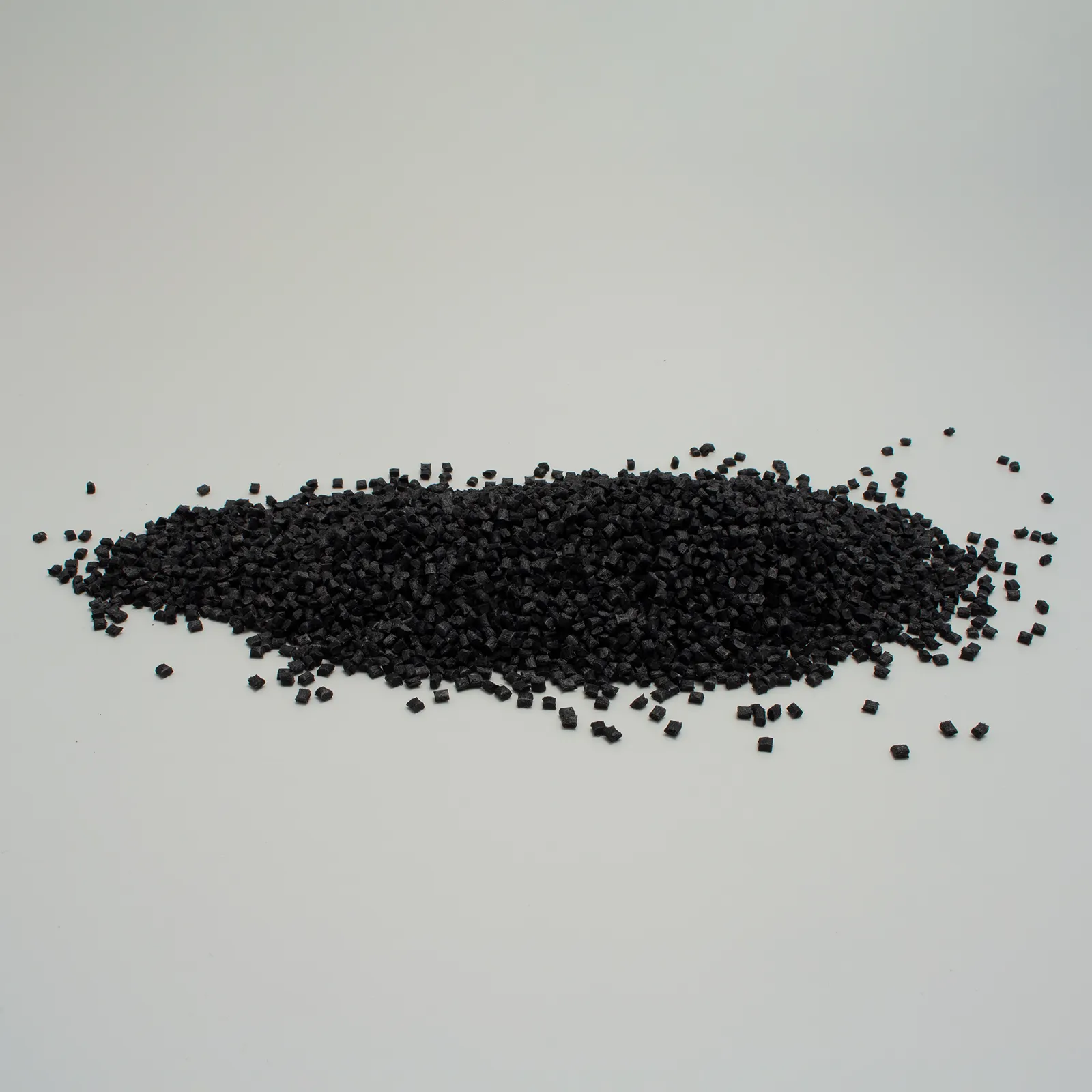 Granuli di plastica nera su uno sfondo bianco, utilizzati per vari progetti di lavorazione e produzione.