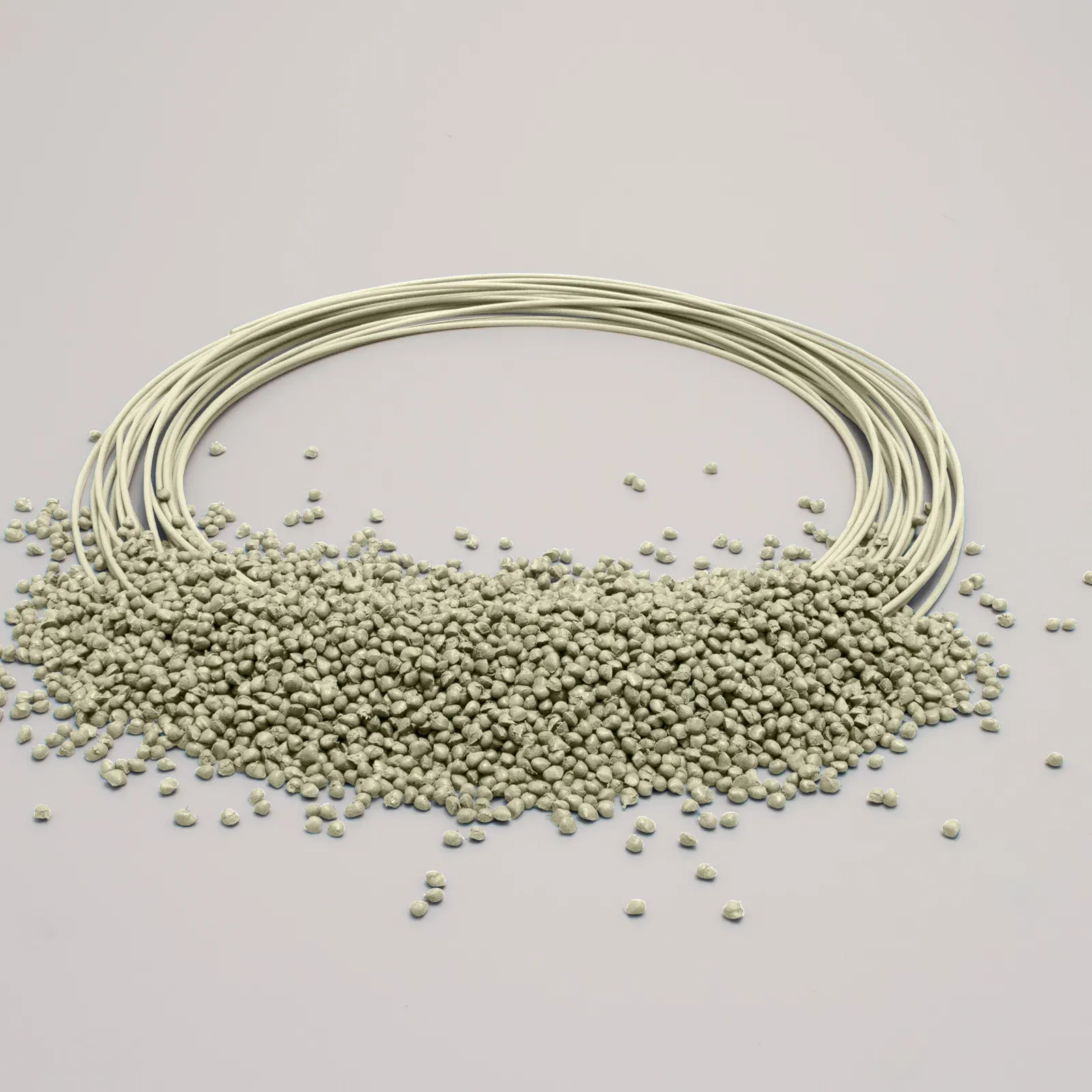 Granuli di plastica beige sparsi accanto a fili di plastica, su uno sfondo chiaro.