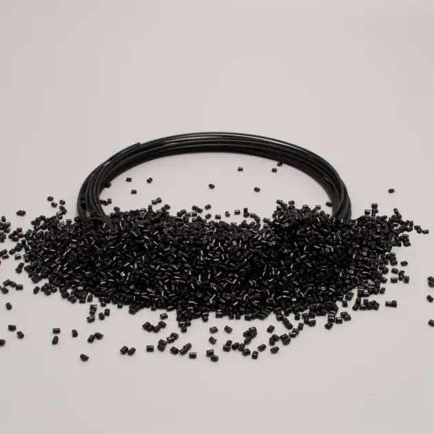 Rete di filament plastico nera con granuli di plastica nera sparsi sul tavolo, ideale per lavorazioni industriali.